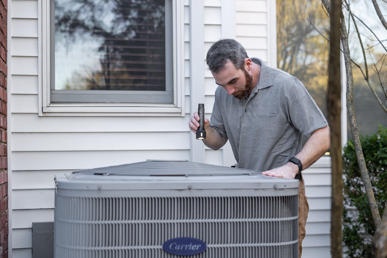 services-01 A technician inspects an outdoor HVAC unit for maintenance.
